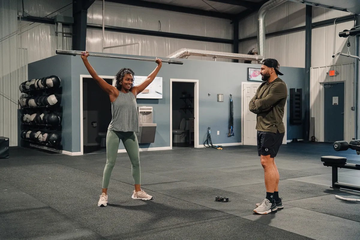 Coach guiding a member through an overhead barbell movement at CrossFit Fig in Grain Valley