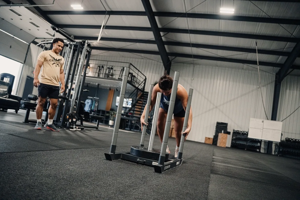 Athlete practicing a HYROX sled push with a coach at CrossFit Fig in Grain Valley